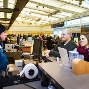 A couple speaking to an airport agent at the check in area