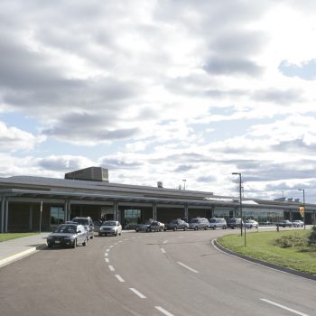cars lined up and parked in front of an airport building
